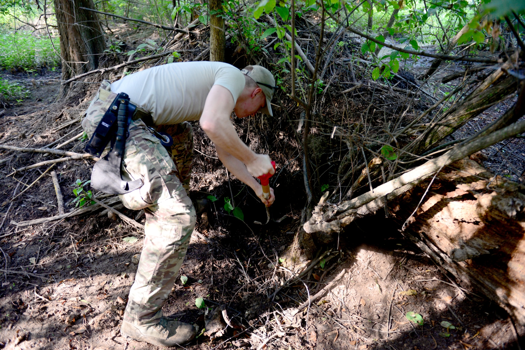 Senior Airman Donal Mesa, 2nd Civil Engineer Squadron explosive ordnance disposal technician, digs out an area to place two 40 pound explosives for a de-watering project in the east reservation woods at Barksdale Air Force Base, La., July 29, 2015. The de-watering project focuses on destroying beaver dams. The dams, which is not where the beavers live, can cause major flooding problems. (U.S. Air Force Photo/Airman 1st Class Luke Hill)

