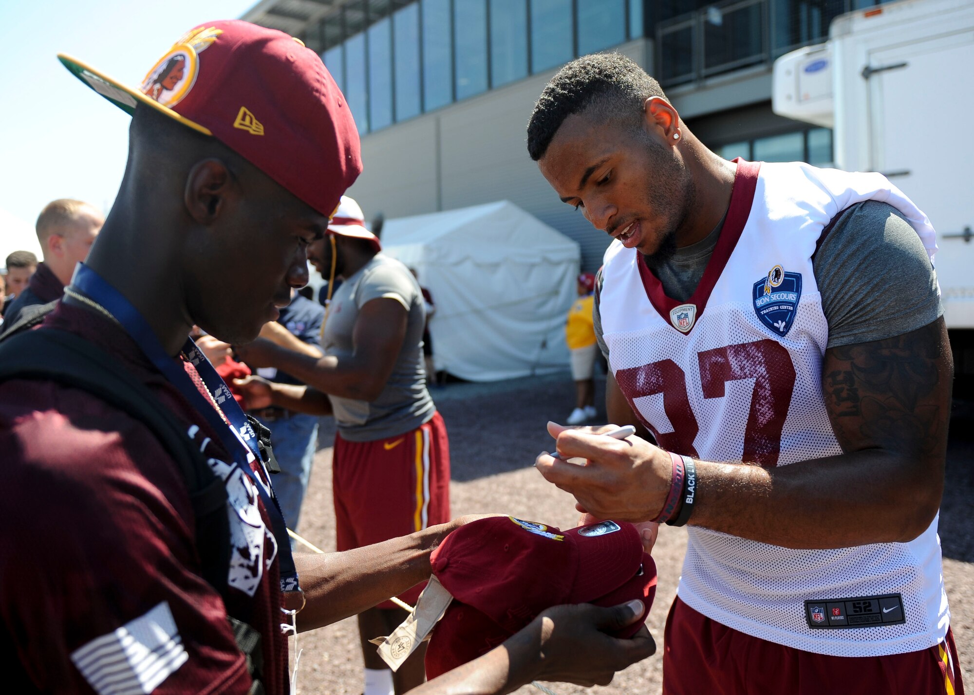 U.S. Air Force Airman 1st Class Dakota, 36th Intelligence Squadron, geospatial intelligence analyst gets his memorabilia signed by Washington Redskin Je'Ron Hamm during the team’s training camp at the Bon Secours Training Center in Richmond, Va., July 31, 2015. U.S. Service members watched the practice from the field sidelines, and met with team players. (U.S. Air Force photo by Staff Sgt. John D. Strong II/Released)