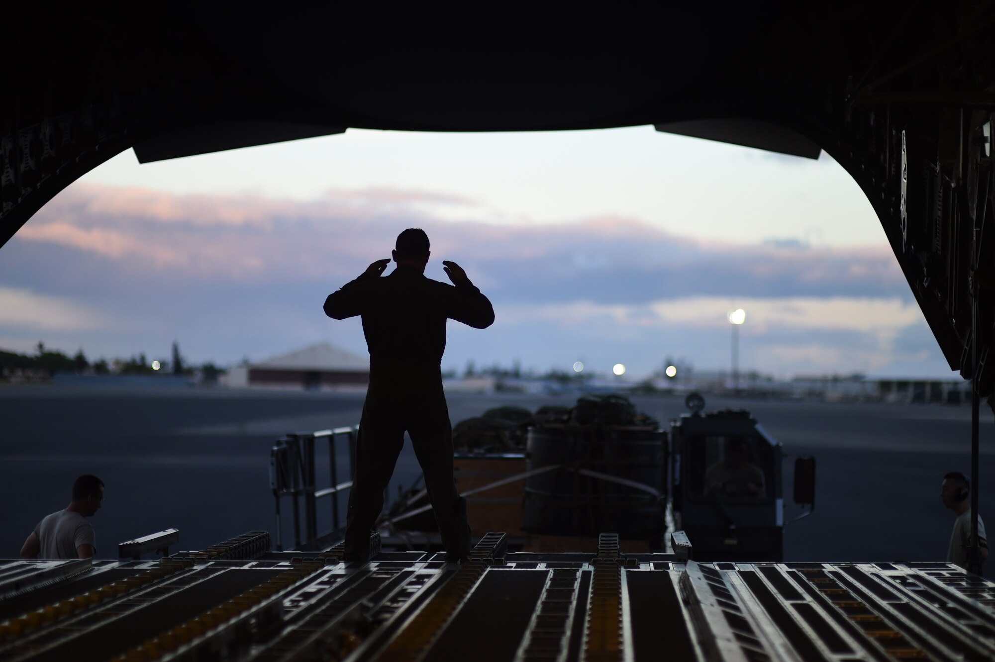 Senior Airmen Caleb Williams, a loadmaster from the 535th Airlift Squadron, guides Airmen from the 647th Logistics Readiness Squadron delivering a combat delivery system to be airdropped during Warrior Day on Joint Base Pearl Harbor-Hickam, Hawaii July 31, 2015. Training simulations included combat maneuvers in a hostile environment, airdrops, and refueling operations. It also included an engine-running crew change of three of the C-17s. (U.S. Air Force photo by Tech. Sgt. Aaron Oelrich/Released)

