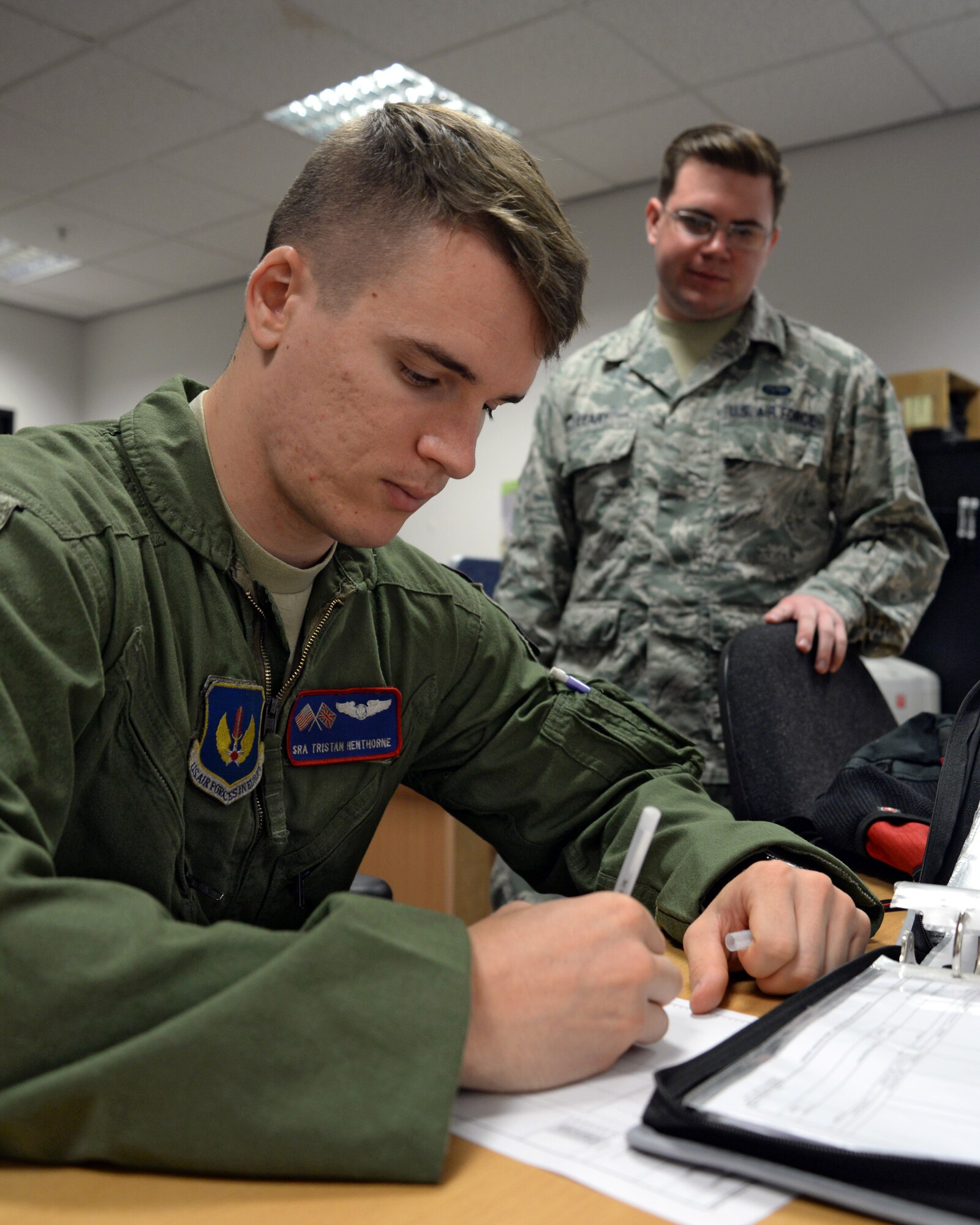U.S. Air Force Senior Airman Tristan Henthorne, left, 351st Air Refueling Squadron instructor boom operator from Belfast, Maine, fills out communication kits forms ready for sign out as U.S. Air Force Senior Airman Brett Leary, 100th Operations Support Squadron combat crew communications technician from Hohenwalk, Tenn., watches July 16, 2015, on RAF Mildenhall, England. The 100th OSS combat crew communications shop ensures aircrew are able to securely communicate during their everyday flying missions. (U.S. Air Force photo by Senior Airman Christine Halan/Released)