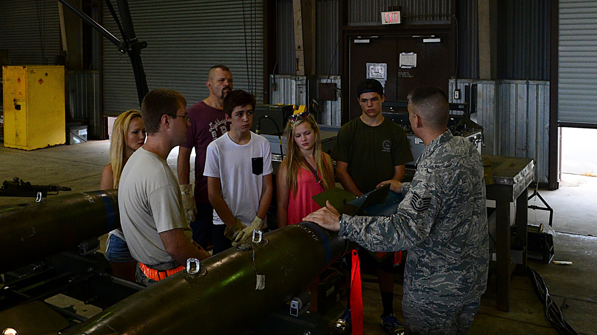 Tech. Sgt. Eric Ybarra, 51st Munitions Squadron flightline maintenance section chief, briefs the Liddell family about various munitions built on Osan Air Base, South Korea, Aug. 5, 2015. Chuck “The Iceman” Liddell, retired American mixed martial artist, visited Osan units with his family during a morale trip. (U.S. Air Force photo/Senior Airman Kristin High)