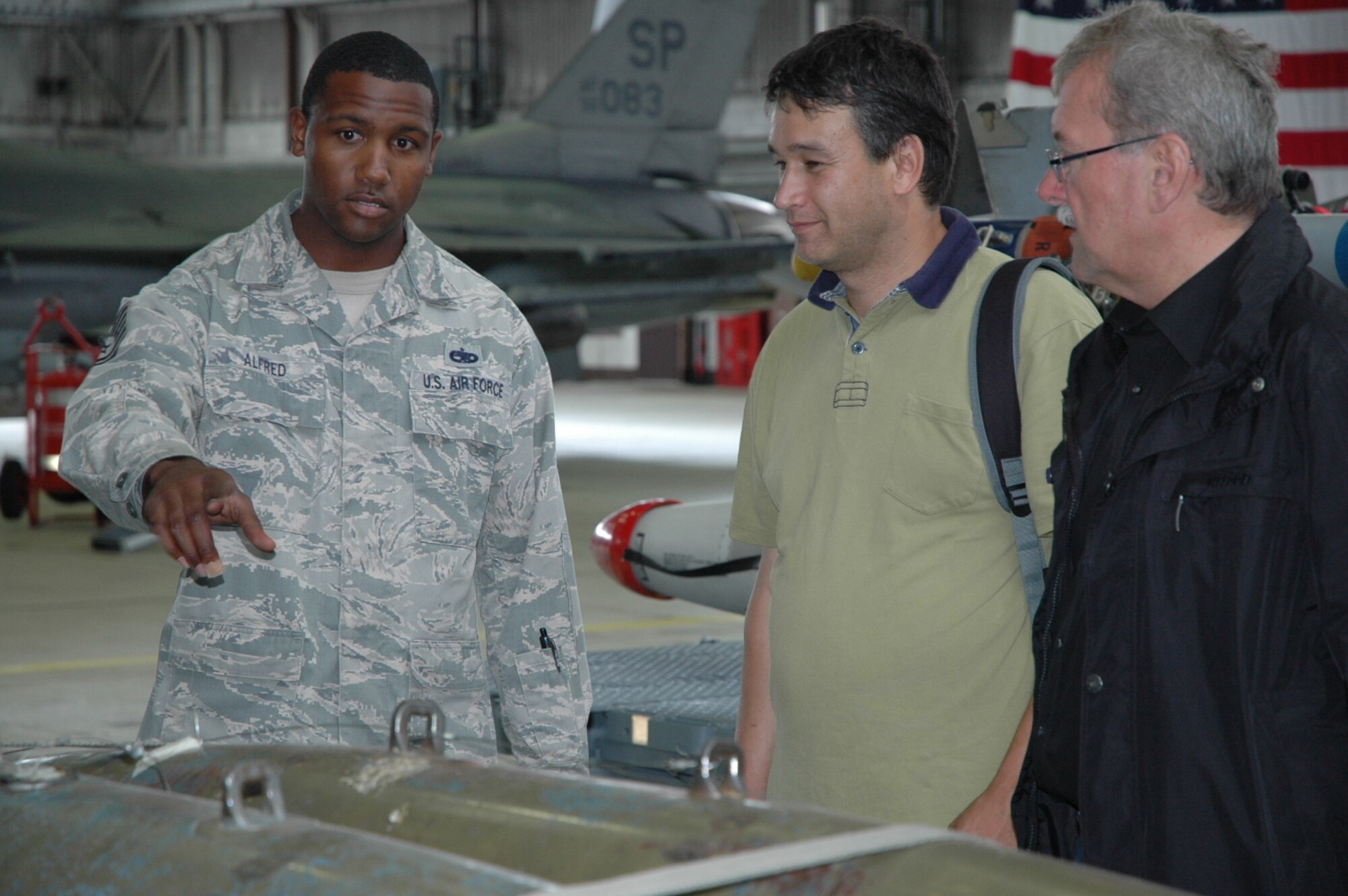 U.S. Air Force Tech. Sgt. Mandingo P. Alfred, 52nd Maintenance Group, talks to a group of members from the Freundeskreis der Luftwaffe e.V. Association about his job as a weapons loader during the association’s visit at Hangar One at Spangdahlem Air Base, Germany, July 13, 2015. The association’s tour included sections of the 726th Air Mobility Squadron as well as various sites from the 52nd Fighter Wing. (U.S. Air Force photo by Iris Reiff/Released) 