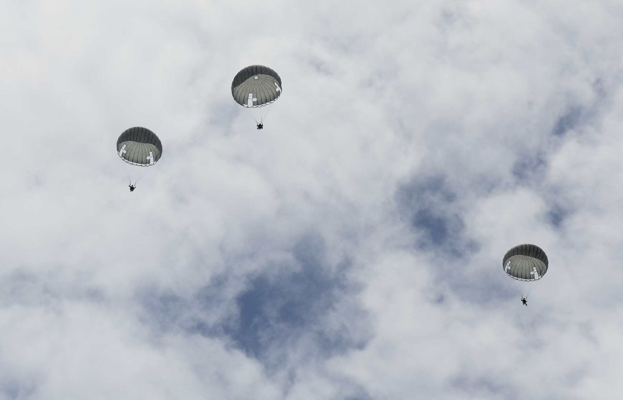 Service members parachute from a C-130 Hercules Aug. 4, 2015, at Andersen Air Force Base, Guam. Airmen, Sailors and Marines assigned to Joint Region Marianas installations took part in regular proficiency training to keep their airborne skills up to date and remain prepared for real-world missions. (U.S. Air Force photo by Airman 1st Class Alexa Ann Henderson/Released)