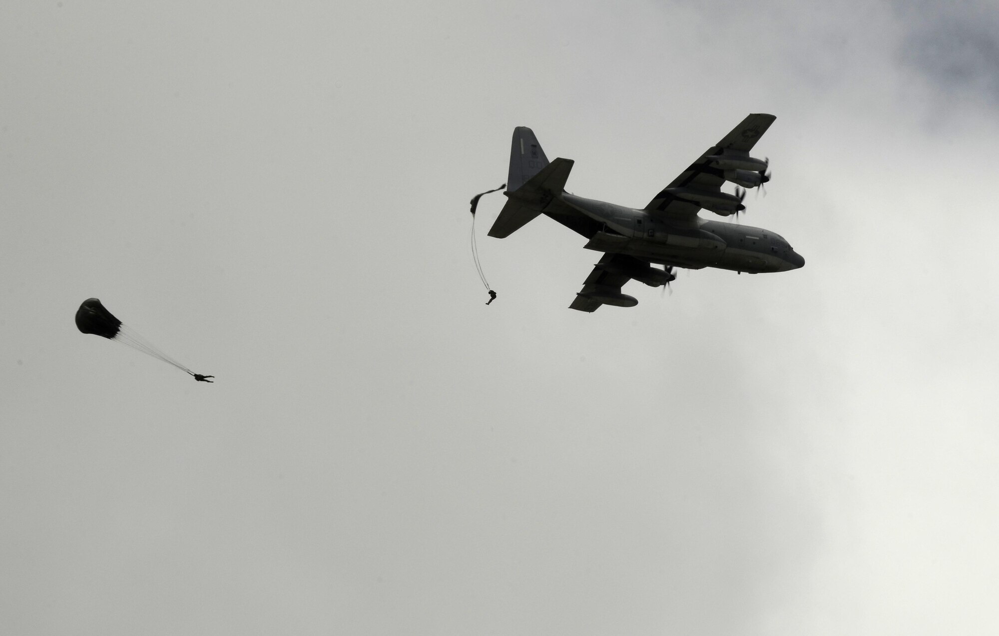 Service members parachute from a C-130 Hercules Aug. 4, 2015, at Andersen Air Force Base, Guam. Airmen, Sailors and Marines assigned to Joint Region Marianas installations took part in regular proficiency training to keep their airborne skills up to date and remain prepared for real-world missions. (U.S. Air Force photo by Airman 1st Class Alexa Ann Henderson/Released)