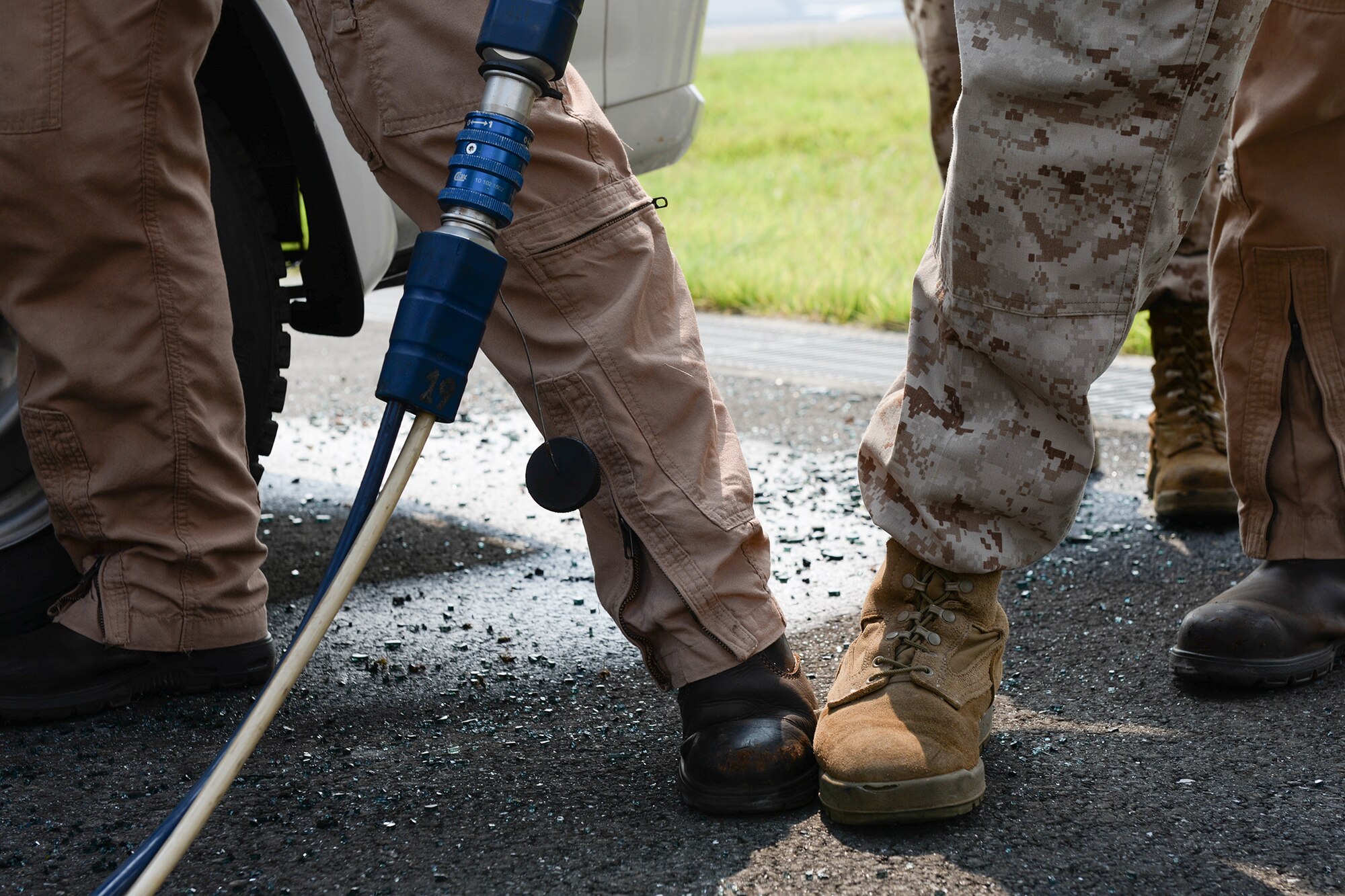 A Marine Corps Air Station Iwakuni firefighter braces a fellow Marine as she uses a hydraulic tool to open a car door at Yokota Air Base, Japan, Aug. 4, 2015. Marines and Yokota Airmen used a variety of tools to remove car windshields, windows and doors  to fee the simulated victims inside. (U.S. Air Force photo by Airman 1st Class Elizabeth Baker/Released)
