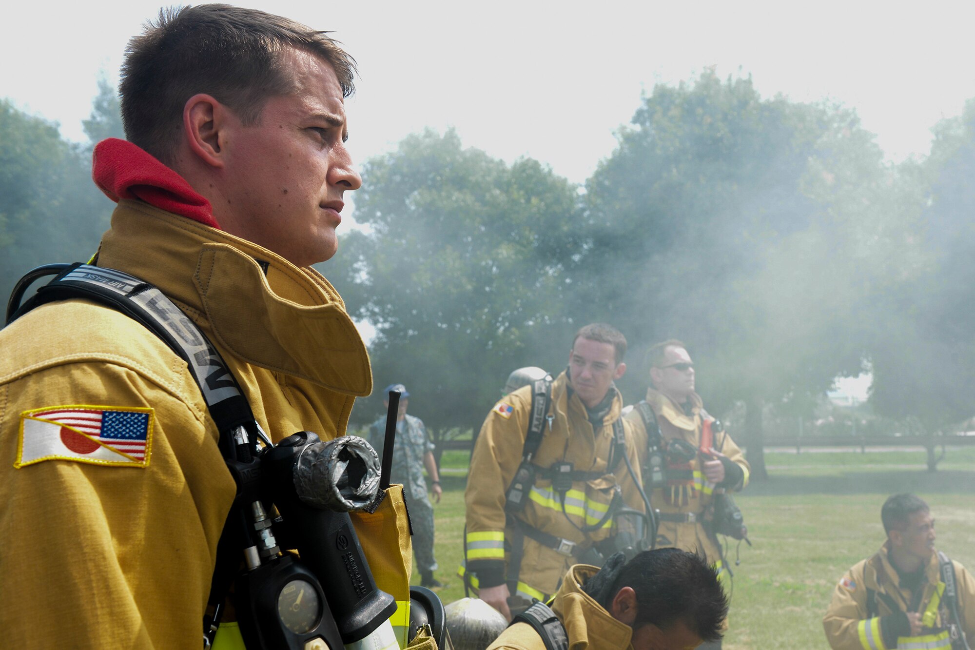 Firefighters with the 374th Civil Engineer Squadron prepare to enter a building containing a controlled blaze at Yokota Air Base, Japan, Aug. 4, 2015. Airmen and Marine firefighters came together for a day of training, utilizing Yokota’s unique training capabilities to enhance emergency readiness. (U.S. Air Force photo by Airman 1st Class Elizabeth Baker/ Released)