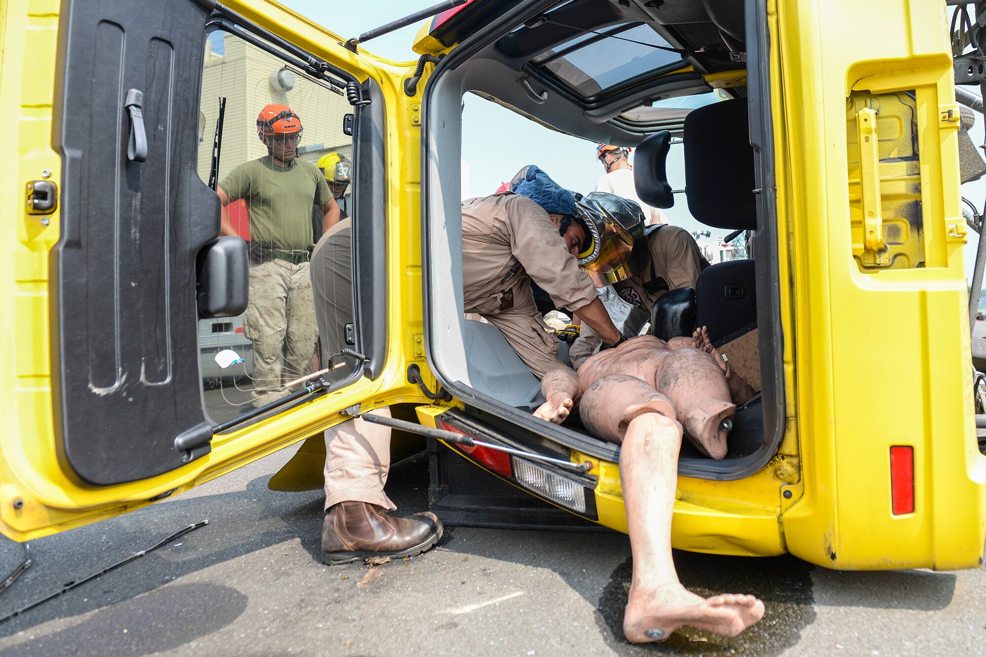 Marine Corps Air Station Iwakuni firefighters practice extracting a mannequin from a simulated car wreck at Yokota Air Base, Japan, Aug. 4, 2015. During emergency response training, Marines first cut through the roof to access the simulated victim and applied emergency first aid to the victim. (U.S. Air Force photo by Airman 1st Class Elizabeth Baker/Released)