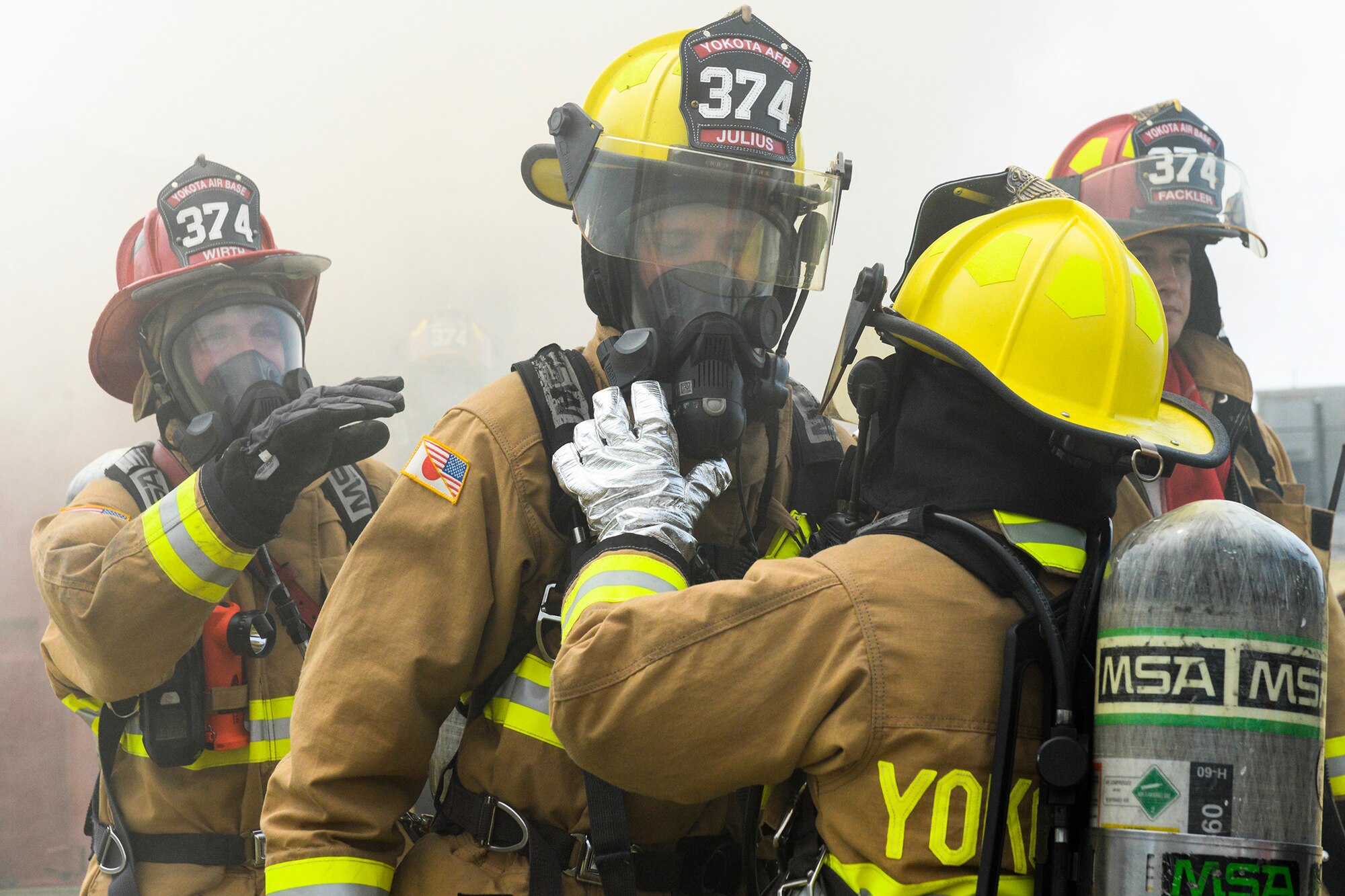 Firefighters with the 374th Civil Engineer Squadron perform buddy checks after fighting a controlled blaze at Yokota Air Base, Japan, Aug. 4, 2015. Yokota uses a variety of facilities to train firefighters, including aircraft, building, and flashover (or suddenly-flaring) fires. (U.S. Air Force photo by Airman 1st Class Elizabeth Baker/Released)