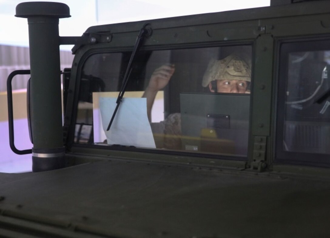 A Marine with Headquarters Platoon, 2nd Naval Air Gunfire Liaison Company, II Marine Expeditionary Force Headquarters Group communicates with Marines in the convoy during combat convoy simulations training aboard Camp Lejeune, North Carolina, August 4, 2015. The combat convoy simulators provide an immersive environment for convoy operations training for command and control procedures in tactical scenarios related to combat operations.