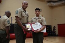 Cpl. Andrew Palacios, a Marine Forces Command data technician, receives certificates and a book for being the honor graduate during Corporals Course from Sgt. Maj. Adam Moore, Headquarters and Service Battalion sergeant major, July 31, 2015.