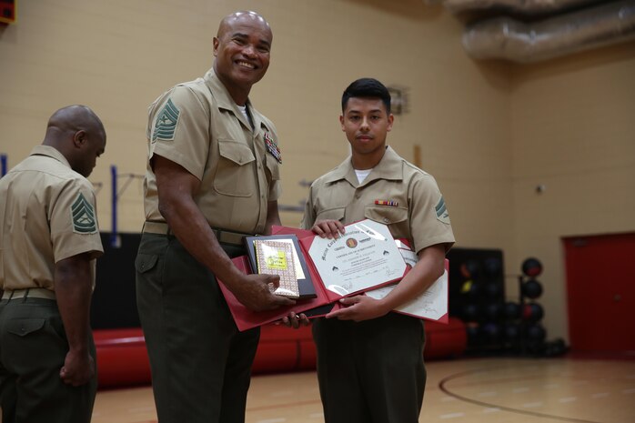 Cpl. Andrew Palacios, a Marine Forces Command data technician, receives certificates and a book for being the honor graduate during Corporals Course from Sgt. Maj. Adam Moore, Headquarters and Service Battalion sergeant major, July 31, 2015.