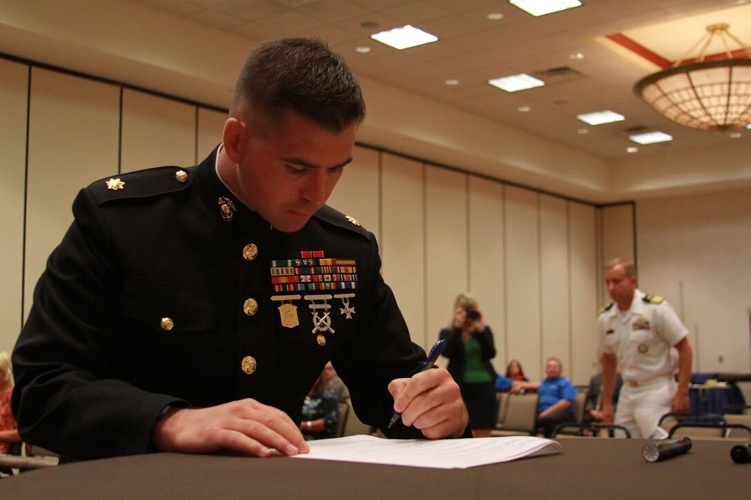U.S. Marine Corps Maj. Gabriel L. Diana, commanding Officer of Recruiting Station Charleston, West Virginia., and a native of Columbus, Ohio, signs the Common Ground Compact July 29, 2015, at the Waterfront Convention Center in Morgantown, West Virginia.  The compact is a combined effort between the Department of Education and the military to reduce the high school dropout rate and ensure students across West Virginia are career and college ready. (U.S. Marine Corps photo by Sgt. Caitlin Brink/Released)