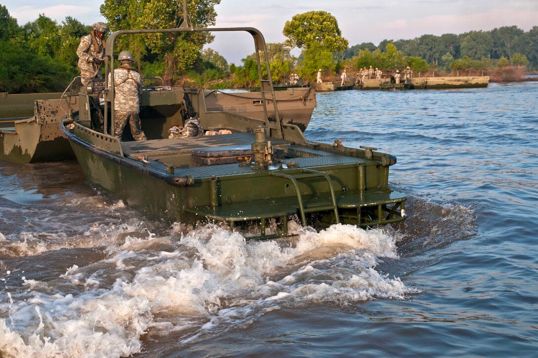 U.S. Army engineers deploy watercraft to push Improved Ribbon Bridge partitions into place to construct a floating bridge across the Arkansas River as part of the River Assault 2015 training exercise on Fort Chaffee, Ark., Aug. 4, 2015.