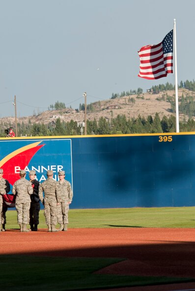 Members of Team Fairchild await the unfurling of the flag on the field as Old Glory waves in the background at Avista Stadium in Spokane, Wash., Aug. 4, 2015. Team Fairchild got to help open events at the Short Season Single A All-Star game. (U.S. Air Force photo/Airman Sean Campbell)