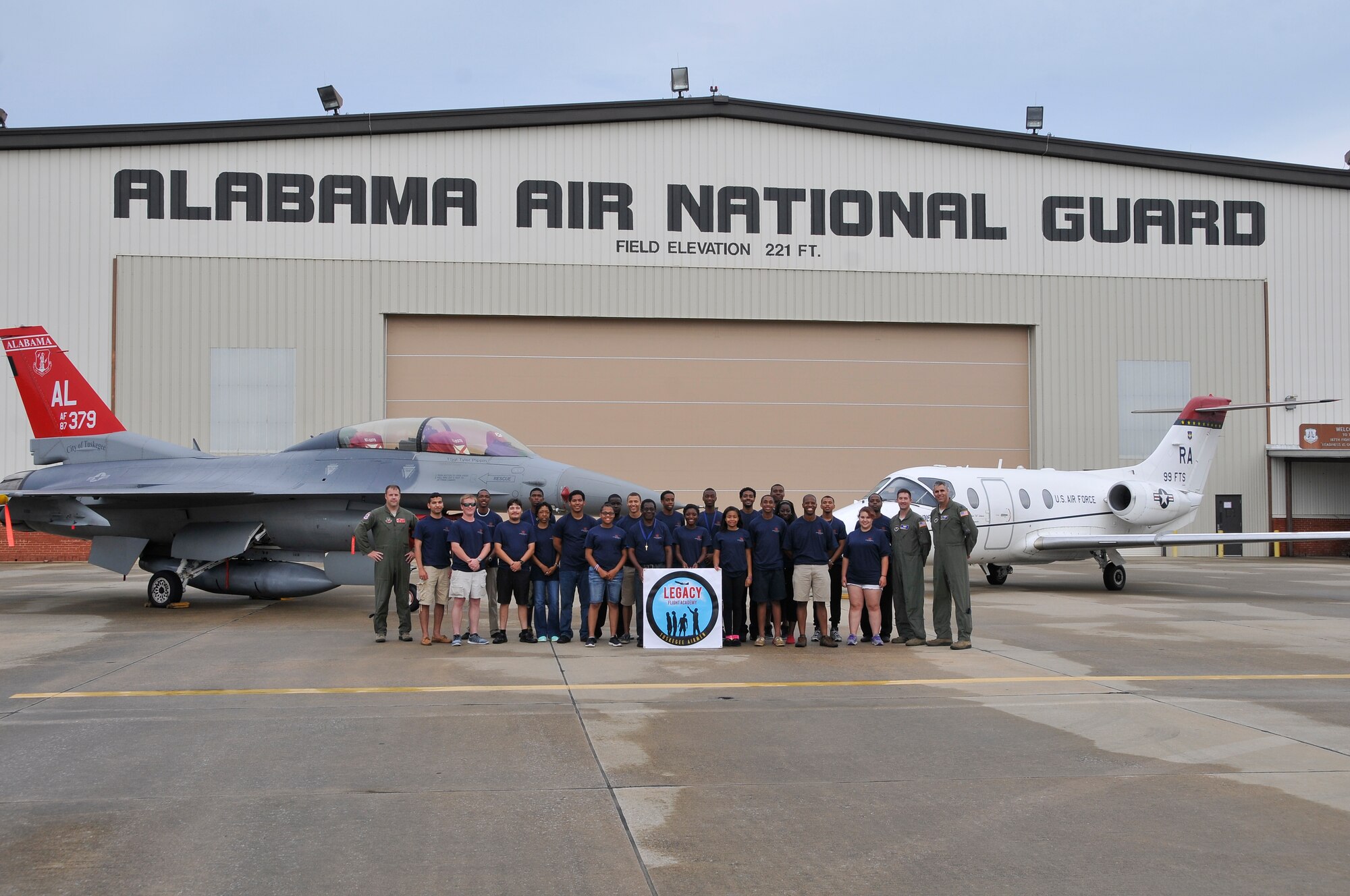 Students of the Legacy Flight Academy  stand in front of an F-16D Fighting Falcon from the 100th Fighter Squadron, Ala. Air National Guard, and a T-1 Jayhawk from the 99th Flying Training Squadron, Randolph Air Force Base, Texas, July 23. The students visited Montgomery Regional Air National Guard Base to learn more about the 187th Fighter Wing’s historic ties to the Tuskegee Airmen. (U.S. Air Force photo by Tech. Sgt. Matthew Garrett\Released)