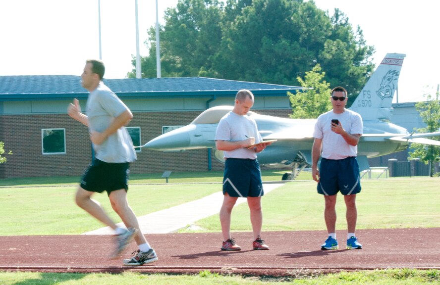Student Flight member John Berryhill works toward improving his one and a half mile run with the completion of another lap as Staff Sgt. Alcides Silva (right) and Tech Sgt. Sean Lindsey (left) keep time Aug. 2, 2015 at Ebbing Air National Guard Base, Fort Smith, Ark. Student Flight works towards encouraging recruits to exceed their own expectations by pushing themselves to achieve more. (U.S. Air National Guard photo by Tech. Sgt. Chauncey Reed/Released)