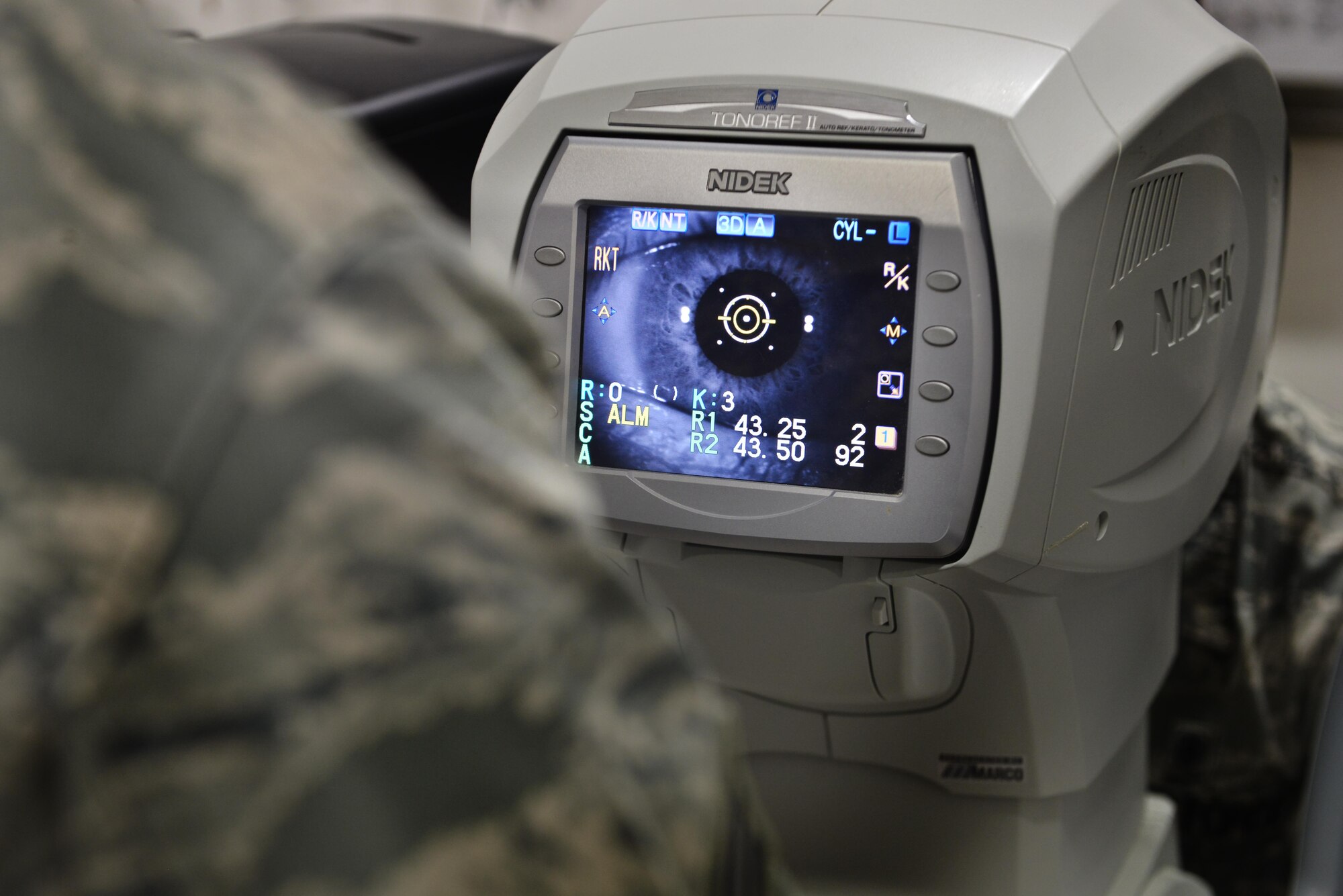 Senior Airman Adlai Ceja, 379th Expeditionary Medical Group optometry clinic, uses a tonometer to blow a small amount of air into a patient’s eye to check its fluid pressure August 7, 2015 at Al Udeid Air Base, Qatar. (U.S. Air Force photo/Staff Sgt. Alexandre Montes)