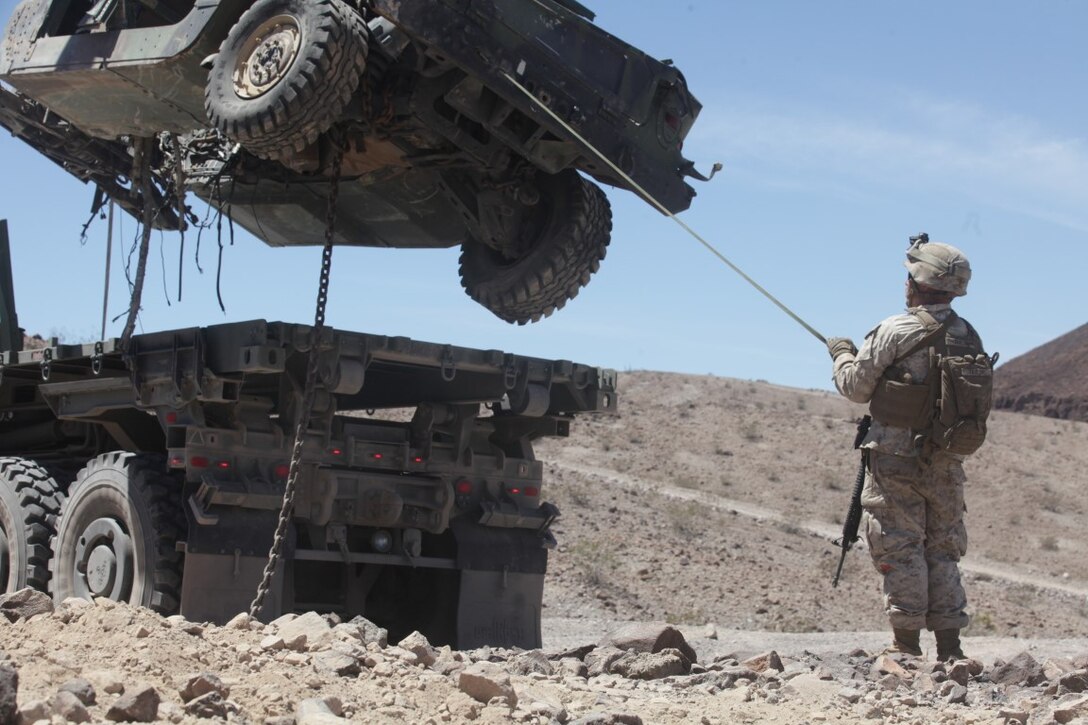 Lance Cpl. Kyle Taylor, a landing support specialist with Combat Logistics Battalion 1, 1st Marine Logistics Group, guides a downed Humvee onto a flatbed truck after extraction during a vehicle recovery mission as part of Integrated Training Exercise aboard Marine Corps Air Ground Combat Center Twentynine Palms, Calif., Aug. 4, 2015. The exercise allowed the Marines to train in a live fire environment and hone their tactical training procedures.