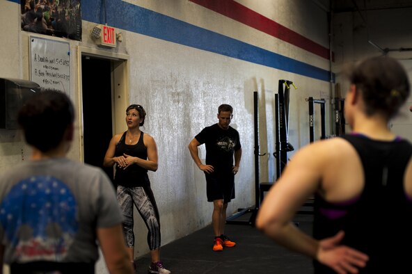A crossfit coach gives instruction to gym goers at a crossfit gym in San Angelo, Texas, Aug. 6, 2015. Air Force Airman 1st Class Sarah M. Bracy, 315th Training Squadron student, attends the gym after eight hours of class. (U.S. Air Force photo by Senior Airman Scott Jackson/released) 