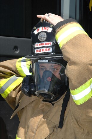 Megan Cornell, firefighter/ nationally registered emergency medical technician – basic, Fire and Emergency Services, Marine Corps Logistics Base Albany, ensures her personal protection equipment fits properly before engaging in a controlled vehicle fire, recently. Cornell is the recipient of MCLB Albany’s Firefighter of the Year Award for 2015; Public Safety Division Civilian Employee of the Year for 2015 and the Marine Corps Firefighter of the Year Award for 2015. 
