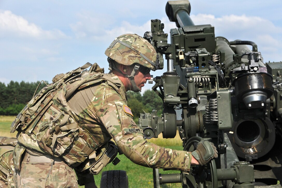 U.S. Army Pfc. Damon Brown adjusts his unit's M777A2 howizter weapons system in preparation for a demonstration of the XM1156 Precision Guidance Kit fuse near Rose Barracks, Germany, July 24, 2015. Brown is a cannon crew member assigned to the2nd Cavalry Regiment's Field Artillery Squadron.