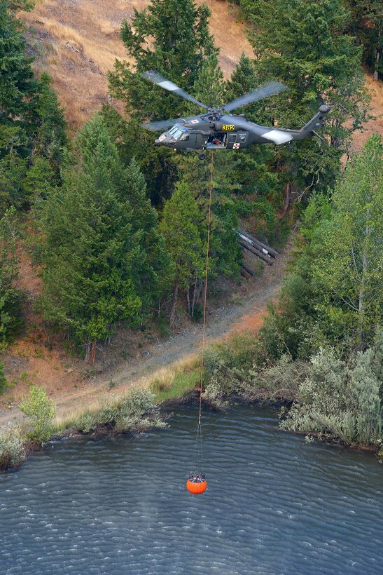 Oregon Army National Guardsmen Lt. Col. Brian Houston, Chief Warrant Officer 2 Rafael Toler and Sgt. Tracy Braeme gain altitude after refilling a Bambi Bucket under their HH-60M Black Hawk helicopter at a water point near the Stouts fire in Canyonville, Ore., Aug. 5, 2015.