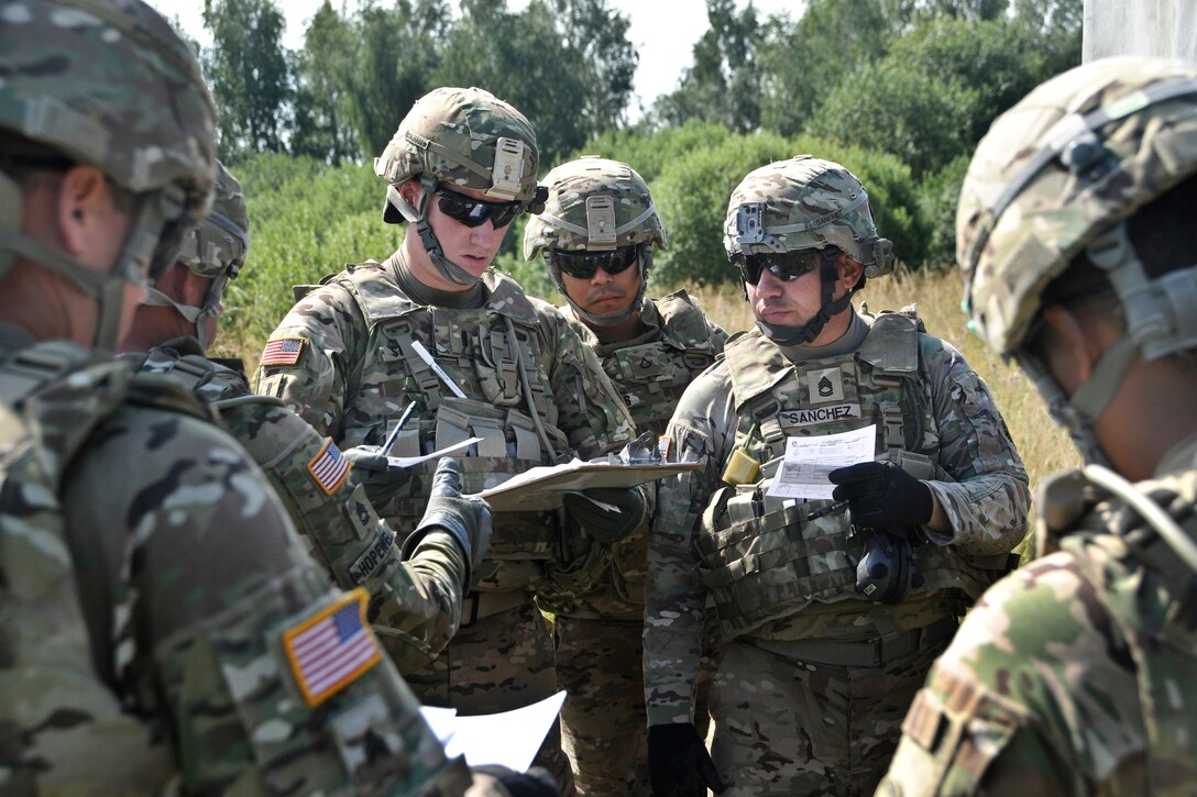 U.S. Army 1st Lt. Alexander Stalnaker, center left, and Army Sgt. 1st Class Gilberto Sanchez, center right, check and compare the coordinates given to their unit's gunnery sergeants during the squadron's preparation for a demonstration of the XM1156 Precision Guidance Kit fuse near Rose Barracks, Germany, July 24, 2015. Stalnaker is a first fire direction officer and Sanchez is a gunnery sergeant assigned to the 2nd Cavalry Regiment's Field Artillery Squadron.