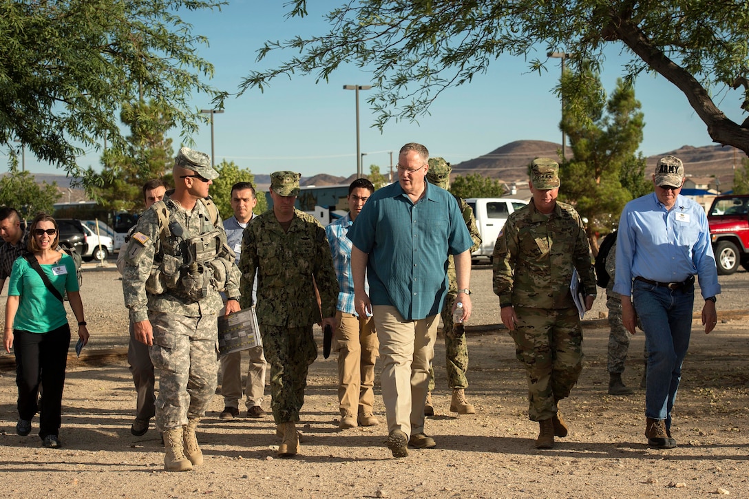 Army Col. Kevin Jacobi, left, the commander of the 11th Armored Cavalry Regiment, escorts Deputy Defense Secretary Bob Work, center, Army Lt. Gen. Pat Donahue, the deputy commanding general of U.S. Army Forces Command, second from right, and Frank Kendall, right, undersecretary of defense for acquisition, technology and logistics, to the Sam Adams club for an exercise briefing at Fort Irwin, Calif., Aug. 5, 2015.