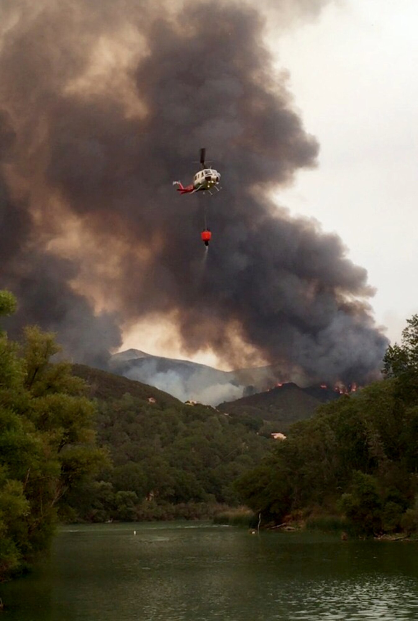 A helicopter transports water from a lake to help extinguish The Rocky Wildfire near Clearlake, California, July 31, 2015. (Courtesy photo)