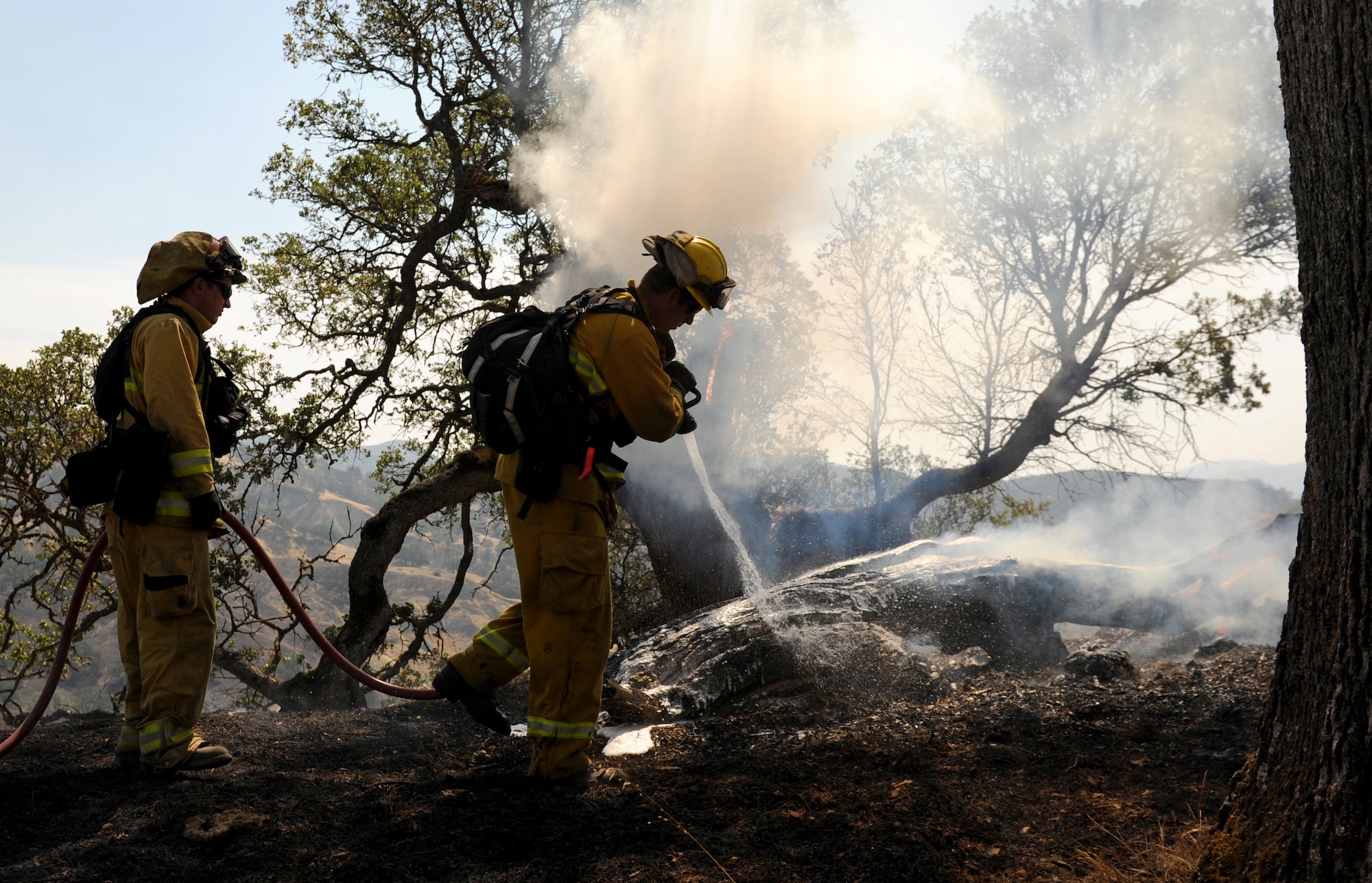 Will Hock (left), 9th Civil Engineer Squadron fire captain, assists Justin Devorss, Linda Fire Protection District engineer, with extinguishing a fire, Aug. 6, 2015, near Clearlake, California. The fire is associated with the Rocky Wildfire that has consumed nearly 70,000 acres in Northern California. (U.S. Air Force Photo by Airman Preston L. Cherry)
