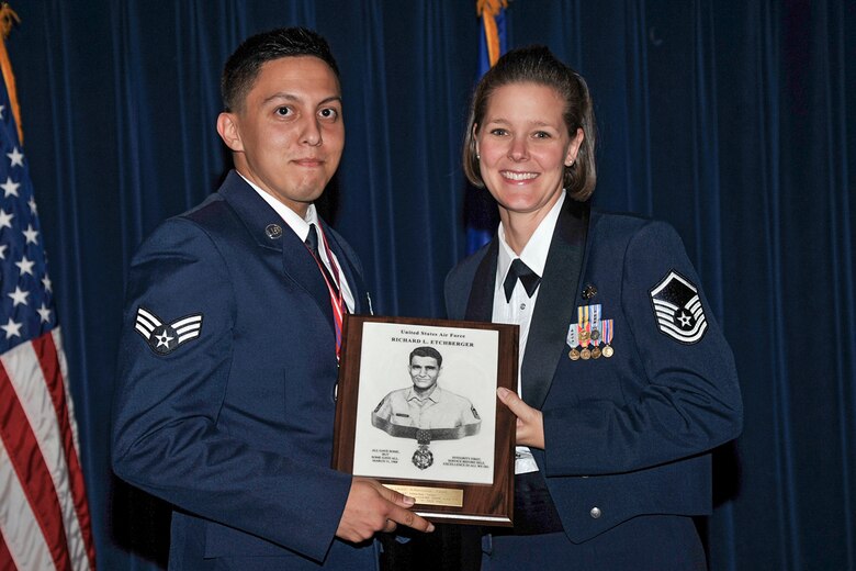 Master Sgt. Michelle James, Air Force Office of Special Investigations, Region 8, NCO-in-charge of financial management, presents Senior Airman Jonathan Vargas, 50th Security Forces Squadron, with the Academic Achievement award during the Airman Leadership School graduation Thursday, July 30, 2015 at Peterson Air Force Base, Colorado. In addition to graduating ALS and earning this award, Vargas also pinned on his Staff Sergeant rank during the event. (U.S. Air Force photo/Robb Lingley)