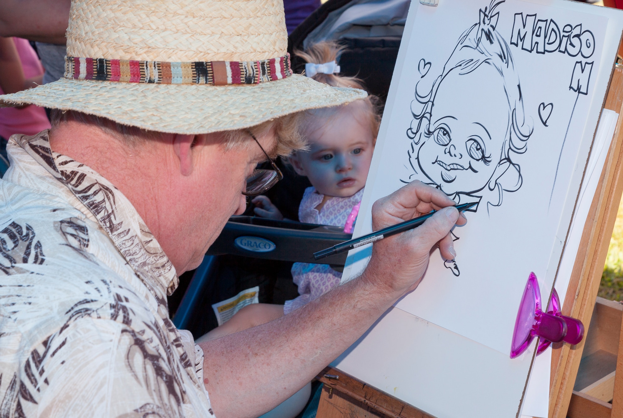 An artist draws a caricature of a child at the Red, White and Blues Base-Wide Picnic at Doughboy Field on Joint Base McGuire-Dix-Lakehurst, N.J., Aug. 5, 2015. The picnic featured face painters, games, bounce houses, free food and included a concert by the Billy Walton Band. (U.S. Air Force photo by Joe Sharp/Released)