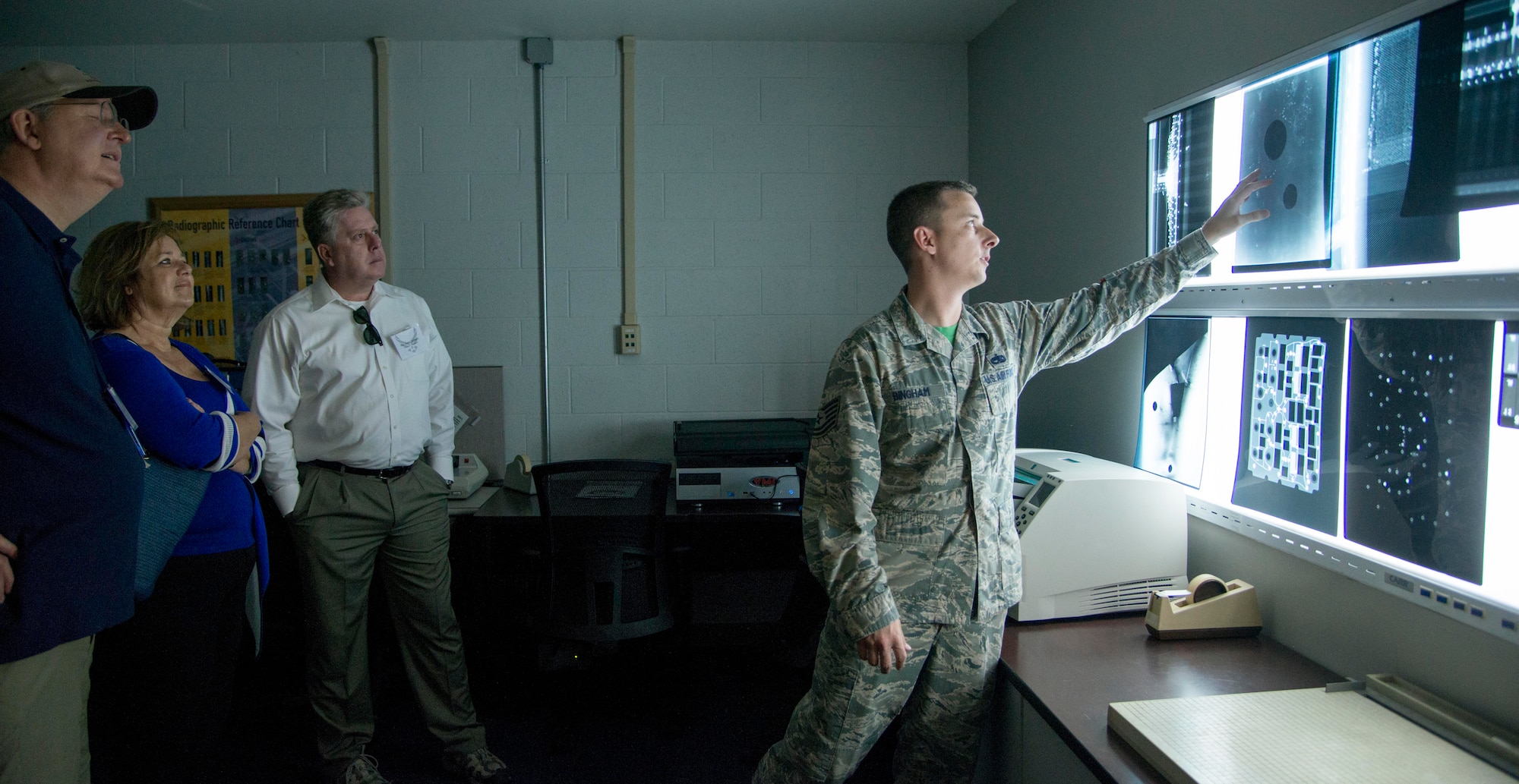 Tech. Sgt. Brandon Bingham, 60th Maintenance Squadron nondestructive inspection lab NCO in charge, shows civic leaders and honorary commanders x-rays taken of an aircraft during a tour of the 60th Maintenance Group July 31, 2015. The NDI flight uses an x-ray machine, ultra sound and ultraviolet light to detect cracks and determine if there is moisture in aircraft parts. (U.S. Air Force photo/Senior Airman Nicole Leidholm)
