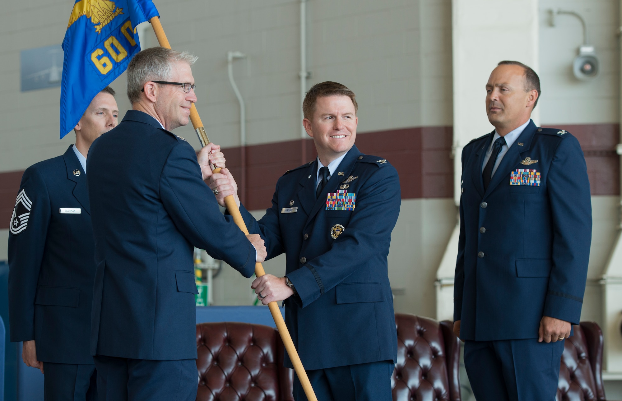 Col. David Mott, right, the outgoing 60th Operations Group commander, looks on as Col. Christopher Maddox accepts the group guidon from Col. Joel Jackson, left, 60th Air Mobility Wing commander, July 30 at Travis Air Force Base, California. (U.S. Air Force photo by Heide Couch)