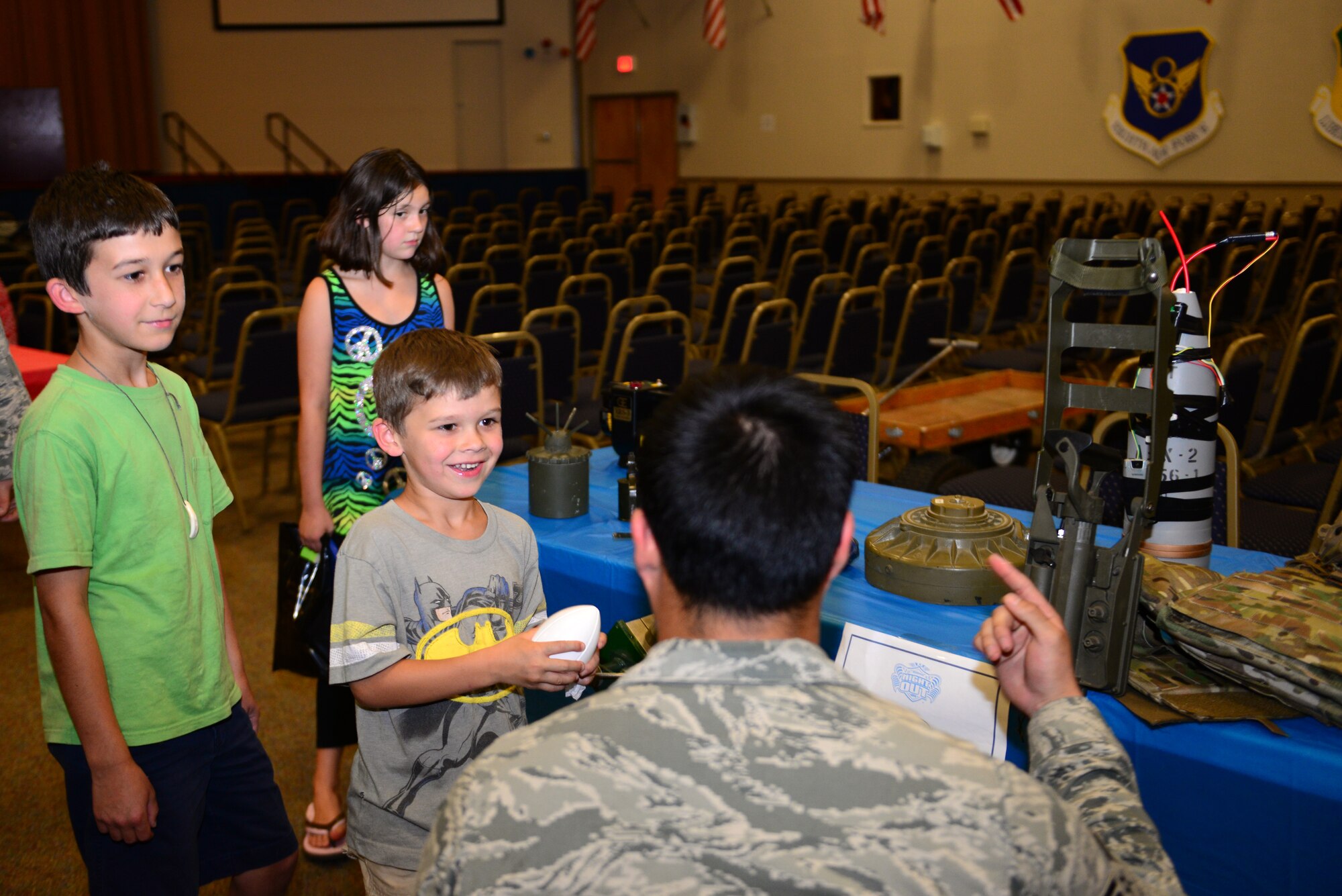 Children watch as a 2nd Civil Engineer Squadron explosive ordnance disposal Airman demonstrates how to use a metal detector to find land mines and other explosives during National Night Out at Barksdale Air force Base, La., Aug. 4, 2015. EOD displayed various equipment such as metal detectors, a bomb suite, old Improvised explosive devices, to showcase their unique job in the Air Force. (U.S. Air Force photo/Airman 1st Class Luke Hill)