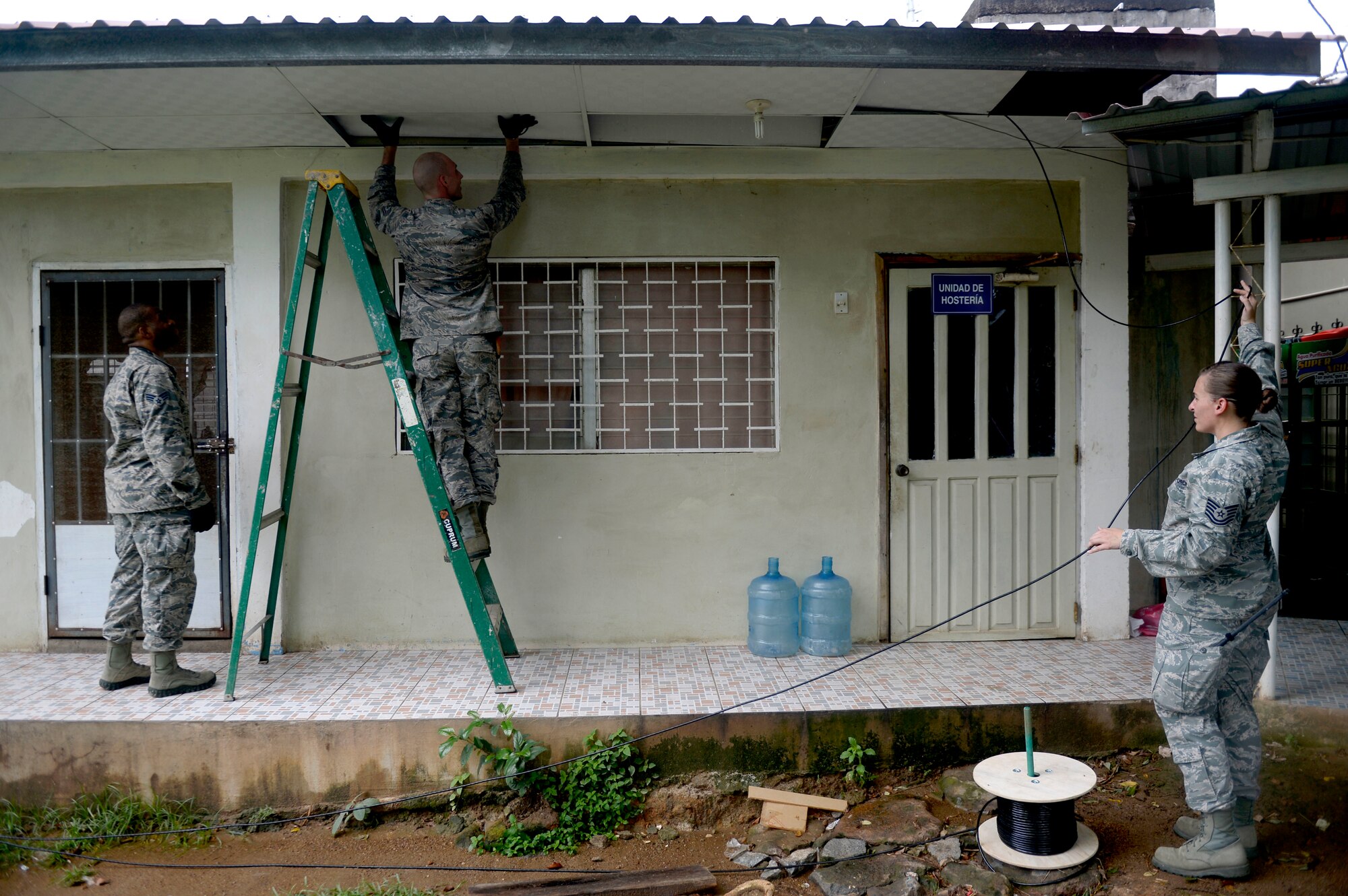 Air Force Tech Sgt. Carl Koenig, radio frequency transmissions technician, center, moves category six cable through ceiling tiles with the help of Senior Airman Trenton Freeman, client systems journeyman, left, and Tech. Sgt. Jasmine Matus, radio frequency transmissions craftsman, all members of the 35th Combat Communications Squadron out of Tinker Air Force Base, in order to restore Internet connectivity to the Dr. Salvador Paredes Hospital in Trujillo, Honduras, June 29. The combat communications Airmen were in the hospital to repair its ailing network as part of the New Horizons Honduras 2015 training exercise. New Horizons was launched in the 1980s and is an annual joint humanitarian assistance exercise that U.S. Southern Command conducts with a partner nation in Central America, South America or the Caribbean. The exercise improves joint training readiness of U.S. and partner nation civil engineers, medical professionals and support personnel through humanitarian assistance activities. (Air Force photo by Capt. David J. Murphy/Released)

