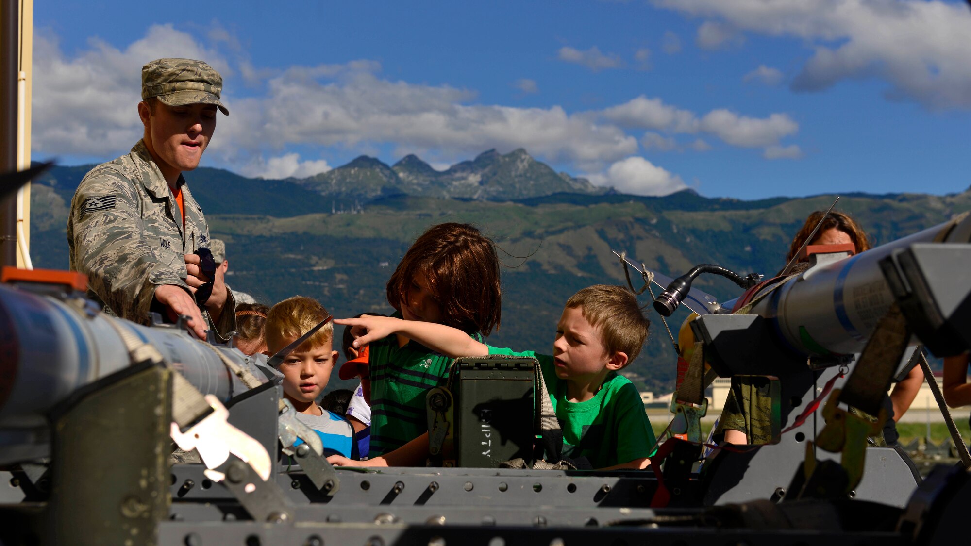 U.S. Air Force Tech. Sgt. Luke Wolf, 31st Munitions Squadron precision guided munitions production NCO in charge, talks with children about working with missiles during the 31st Munitions Squadron family day, July 31, 2015, at Aviano Air Base, Italy. The event provided families the opportunity to view munition equipment and an orientation of work accomplished at the squadron. (U.S. Air Force photo by Airman 1st Class Cary Smith/Released)