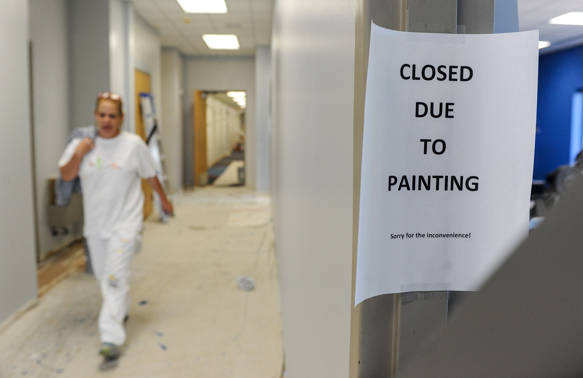 Dona Watson, a contractor, takes a break from painting a hallway wall in the McAdoo Sports and Fitness Center at Minot Air Force Base, N.D., July 30, 2015. In addition to a fresh coat of paint, fitness center patrons will soon be able to enjoy new flooring throughout the building and a refinished floor in the basketball court. (U.S. Air Force photo/Senior Airman Stephanie Morris)
