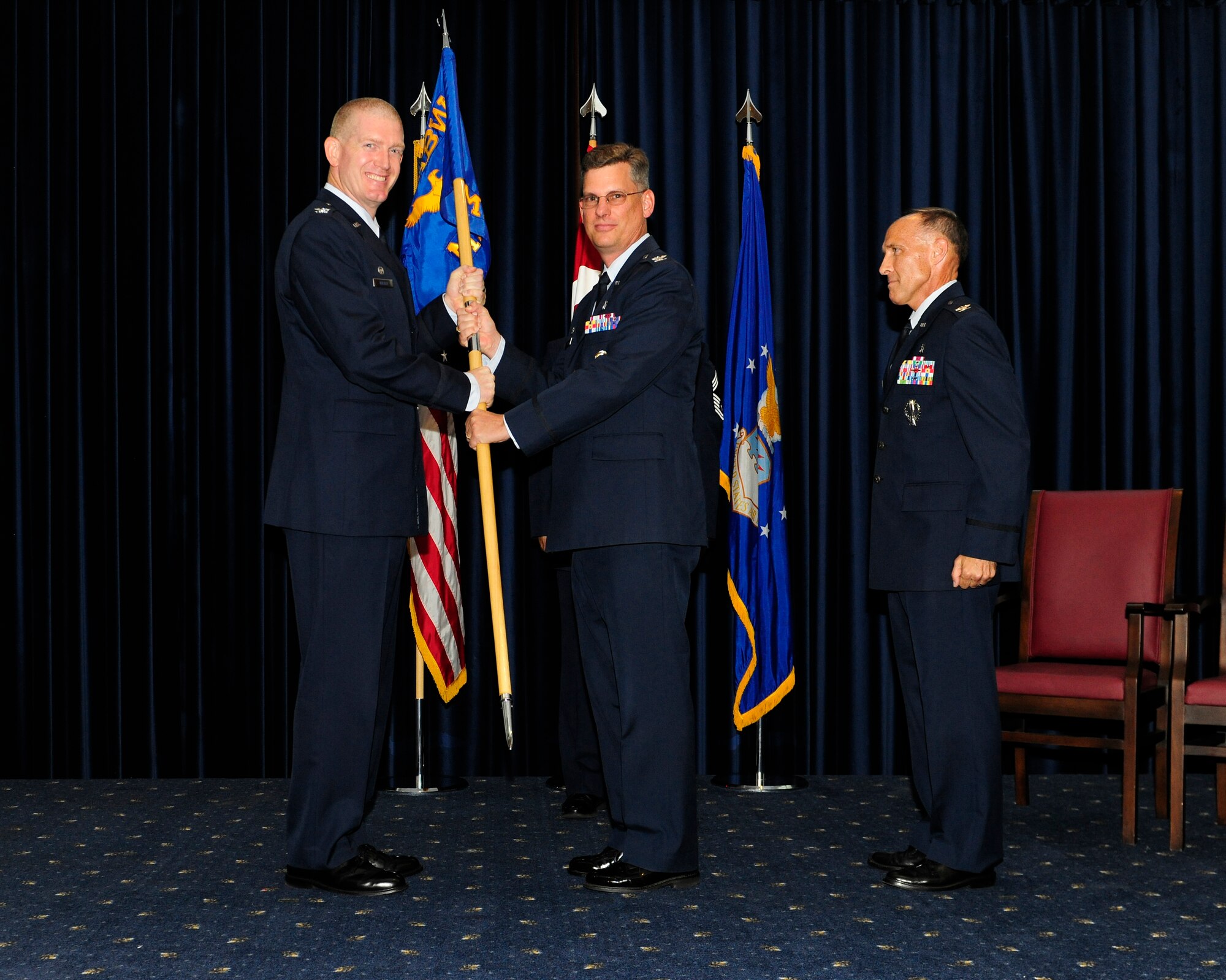 Col. John Walker, 39th Air Base Wing commander, passes the guidon to Col. Thomas Bacon, 39th Medical Group commander, during the 39th MDG change of command ceremony Aug. 7, 2015, at Incirlik Air Base, Turkey. The ceremony signified the acceptance of command by the incoming commander. (U.S. Air Force photo by Senior Airman Krystal Ardrey/Released) 