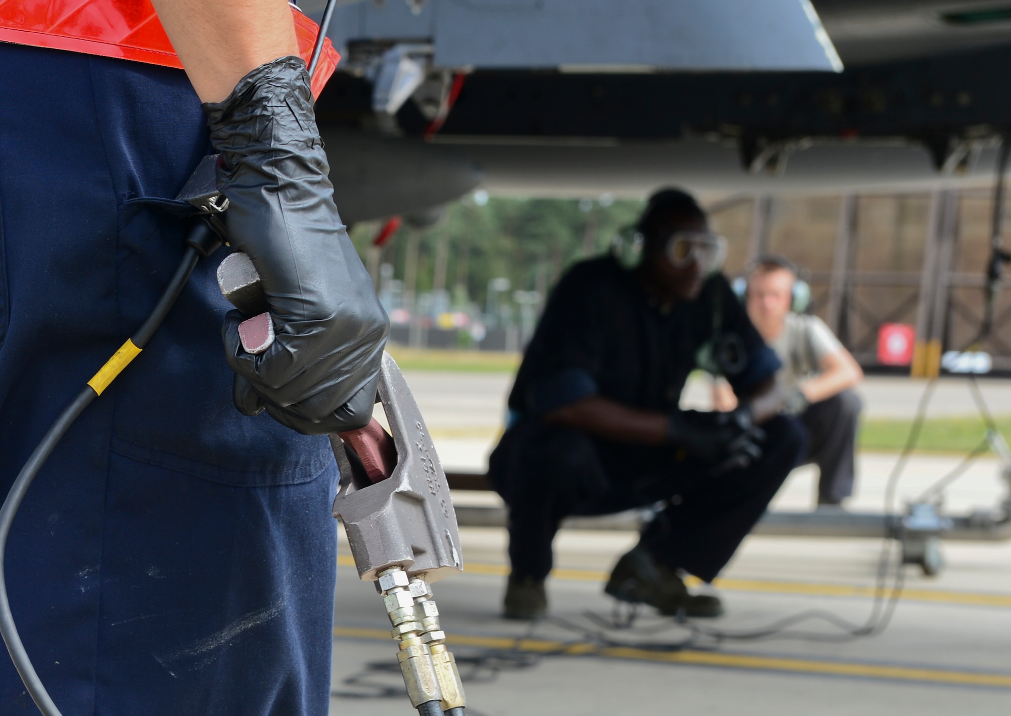 An Airman from the 48th Aircraft Maintenance Squadron tactical aircraft maintenance crew chief refuels an F-15E Strike Eagle during a hot-pit refueling, while other crew chiefs monitor the fuel tank at Royal Air Force Lakenheath, England, Aug. 5, 2015. Hot-pit refueling are conducted while engines are still running, refueling one tank at a time. These types of refueling allow aircraft to return to flight faster. (U.S. Air Force photo by Senior Airman Dawn M. Weber/Released)