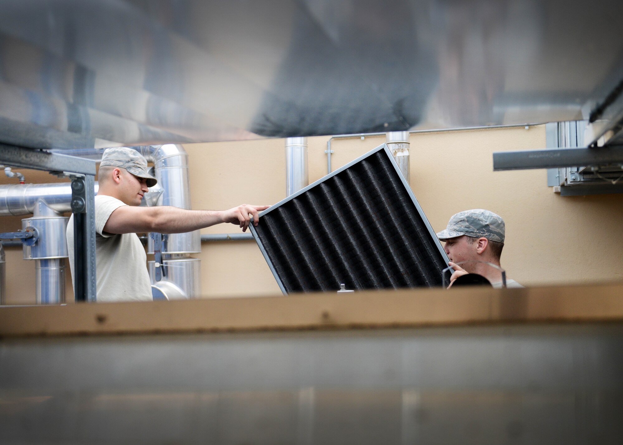 U.S. Air Force Airmen 1st Class Aaron Ohlemacher and Jedadiah Floyd, 31st Civil Engineer Squadron heating, ventilation, air conditioning and refrigeration technician, cleans an air filter, July 29, 2015, at Aviano Air Base, Italy. HVAC Technicians clean air filters every quarter, ensuring all machine parts are properly working. (U.S. Air Force photo by Airman 1st Class Deana Heitzman/Released)       