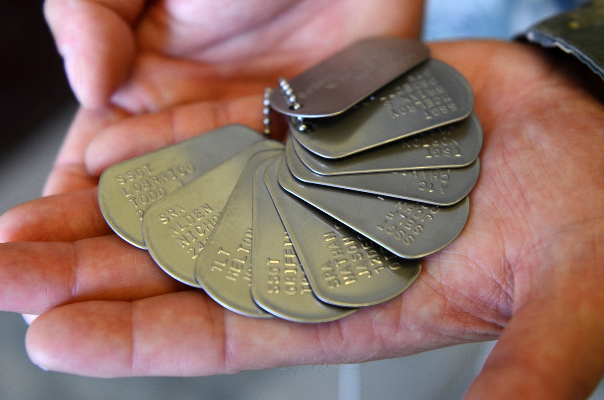 Staff Sgt. Scott Ray, 36th Security Forces Squadron assistant flight chief, holds 10 memorial dog tags Aug. 6, 2015, at Andersen Air Force Base, Guam. The dog tags were part of a memorial honoring the 10 defenders who lost their lives in Operation Iraqi Freedom and Operation Enduring Freedom. (U.S. Air Force photo by Airman 1st Class Alexa Ann Henderson/Released)