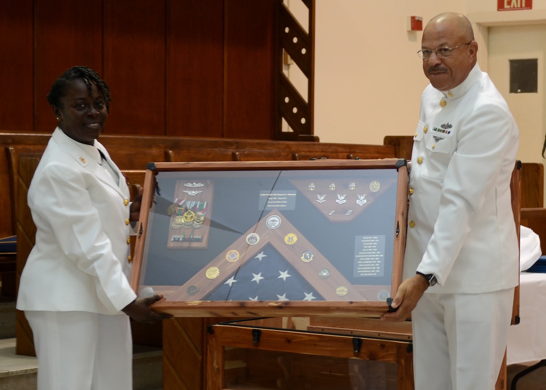 Senior Chief Hospital Corpsman Charles Wyllie (right) presents a retirement shadow box to Naval Hospital Jacksonville, Fla., Command Master Chief Bennora Simmons during her retirement ceremony, July 31. Simmons, a native of Charleston, S.C., retired after 30 years of naval service. 