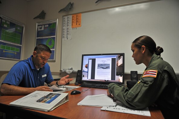 Brian Buss, 97th Training Squadron boom operator instructor, and U.S. Air Force Senior Airman Mary Claire Bolo, 203rd Air Refueling Squadron boom operator student, Hawaii Air National Guard, conduct a pre-briefing before stepping inside a U.S. Air Force KC-135 Stratotanker refueling aircraft Boom Operator Weapons System Trainer at Altus Air Force Base, Oklahoma, July 30, 2015. The briefing prepares students for what they may encounter during the training simulation and allows them to ask any last minute questions before being evaluated. (U.S. Air Force photo by Senior Airman Dillon Davis)