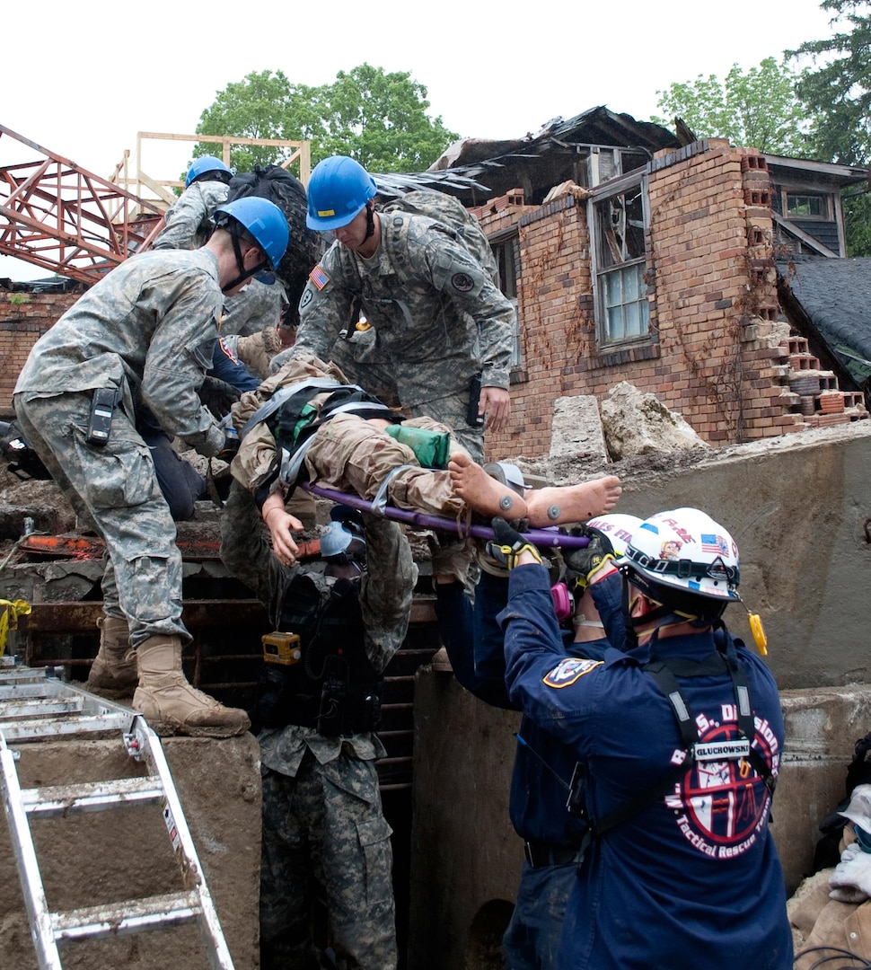 Members of the 53rd Civil Support Team, Indiana National Guard, join efforts with the Indiana Department of Homeland Security tactical rescue team to pull a mock victim from the rubble during National Level Exercise 2011 at the Muscatatuck Urban Training Complex, Ind., May 16, 2011. NLE 2011 was a full-scale exercise meant to represent the destruction following a 7.7 magnitude earthquake along the New Madrid fault line and examined the government's ability to implement local, state, and federal catastrophic earthquake response plans. The National Guarded coordinated response efforts with U.S. Northern Command and federal, state and local agencies throughout the exercise.