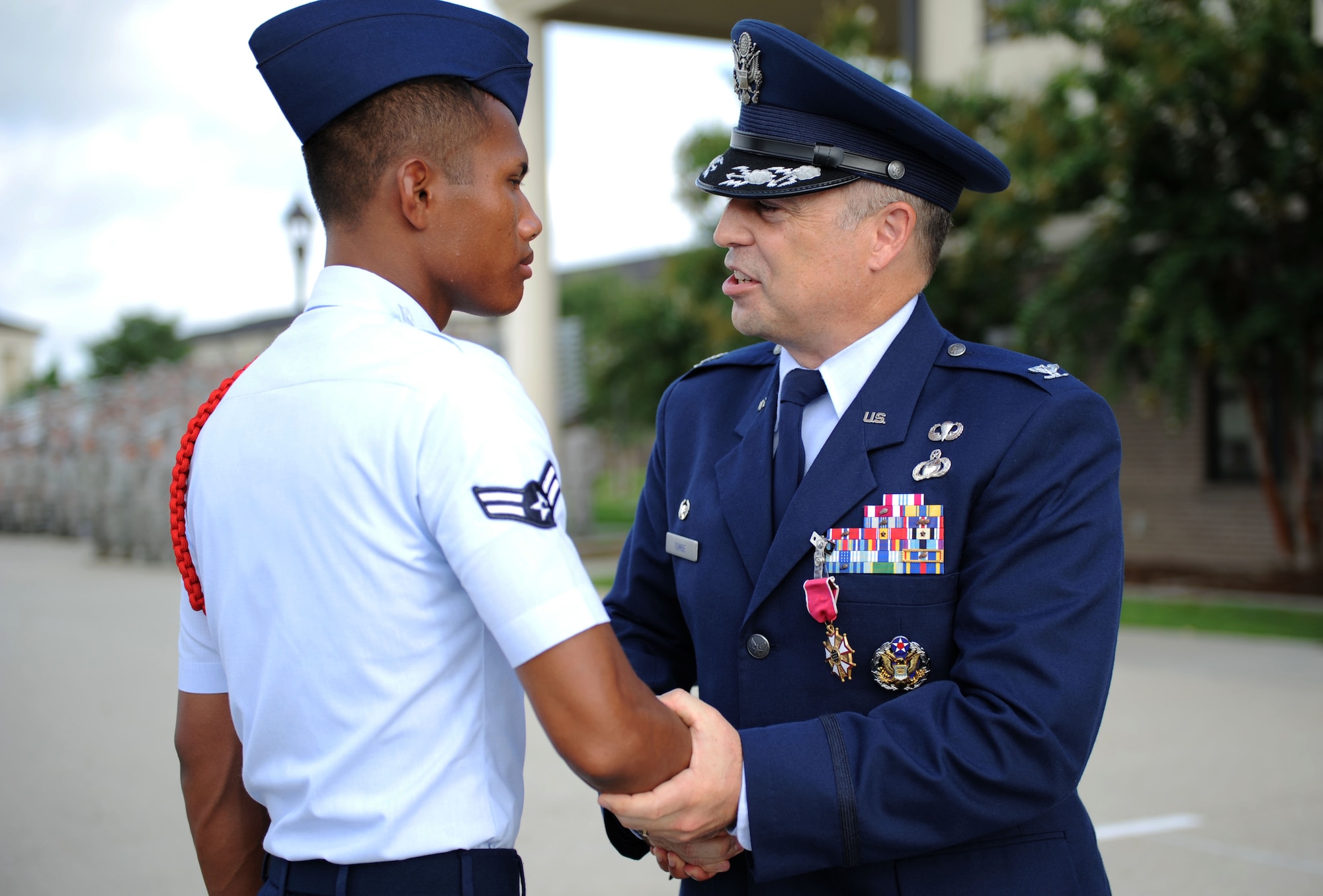 Airman 1st Class Rithy Heng, 334th Training Squadron student, receives a coin from Col. George Tombe, outgoing 81st Training Group commander, during a change of command ceremony, August 7, 2015, Keesler Air Force Base, Miss. Tombe has been selected to serve as the financial management and comptroller director at Headquarters USAFE-AFAFRICA. (U.S. Air Force photo by Kemberly Groue)