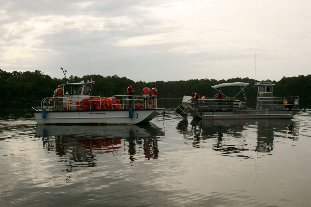 Two response boats set-up a boom to collect simulated oil during a facility response training exercise conducted to ensure top performance in the possible situation of an oil spillage at Marine Corps Air Station Cherry Point, North Carolina, Aug. 4, 2015. Typically referred to as Open Water Spill Team Training, the annual training is mandatory under federal and state laws such as the Clean Water Act and the Oil Pollution Act of 1990. Spill response measures are put into place to provide control, containment and cleanup in order to prevent injury and damage to personnel, property, and the environment.