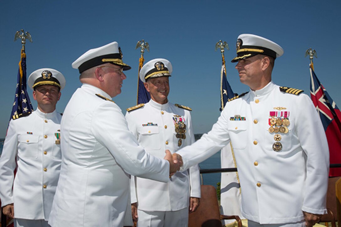 Rear Adm. Michael Jabaley (second from left) shakes hands with Rear Adm. (select) Moises DelToro (right) as they pass command of NUWC from Jabaley to DelToro at a ceremony held at Division Newport on July 31. Looking on are Vice Adm. William Hilarides (second from right), commander, NAVSEA  and Lt. Philip Carson (left), Naval Station Newport chaplain.