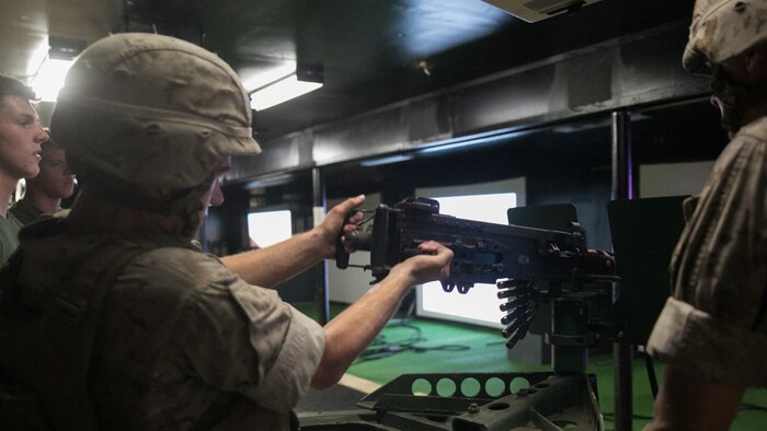 A Marine with Weapons Company, 2nd Battalion, 2nd Marine Regiment, racks the bolt of an M2 50-caliber machine gun back during training at the Indoor Simulated Marksmanship Trainer at Marine Corps Base Camp Lejeune, N.C., Aug. 5, 2015. Although the ISMT weapons are powered by compressed air, misfires with real weapons are obstacles Marines must learn to overcome quickly. 