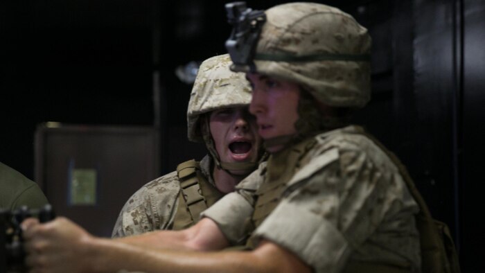 A Marine with Weapons Company, 2nd Battalion, 2nd Marine Regiment, motivates another member of his platoon to keep firing during training at the Indoor Simulated Marksmanship Trainer at Marine Corps Base Camp Lejeune, N.C., Aug. 5, 2015. Marines with the unit conducted training on the virtual range to improve weapon proficiency without leaving a large logistical footprint. 